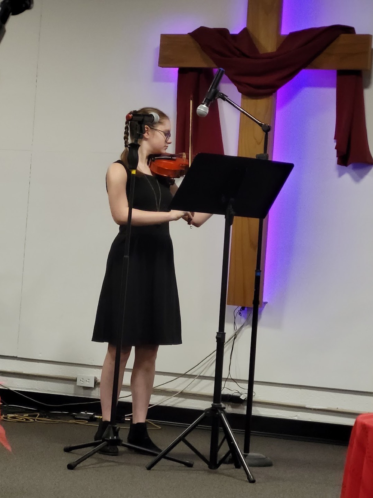 A CCA student playing violin beneath the cross at the Christmas program