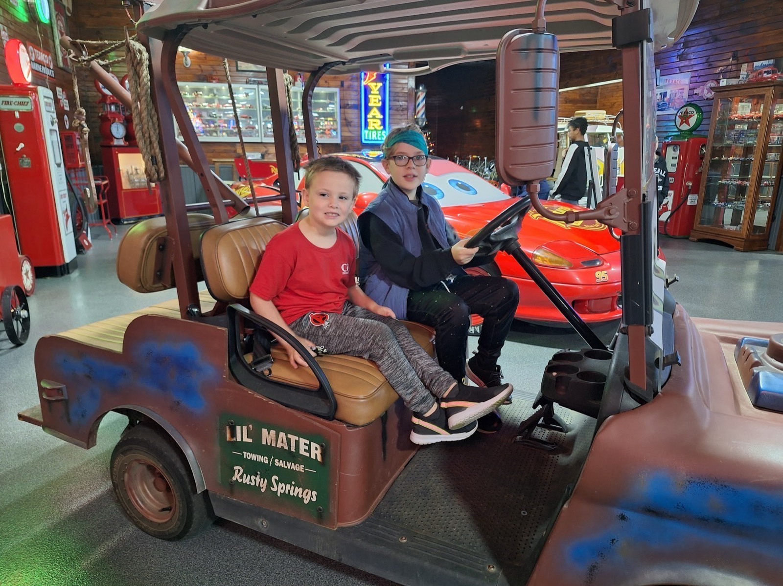 Two smiling students aboard a display cart at the auto museum