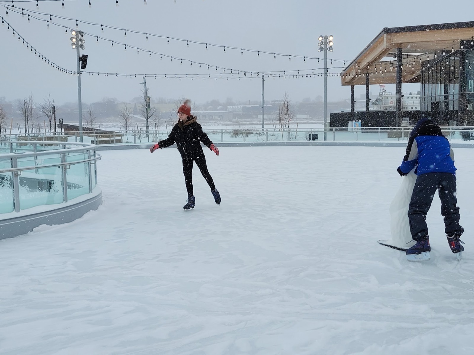 Students ice skating together at an outdoor rink in the snow
